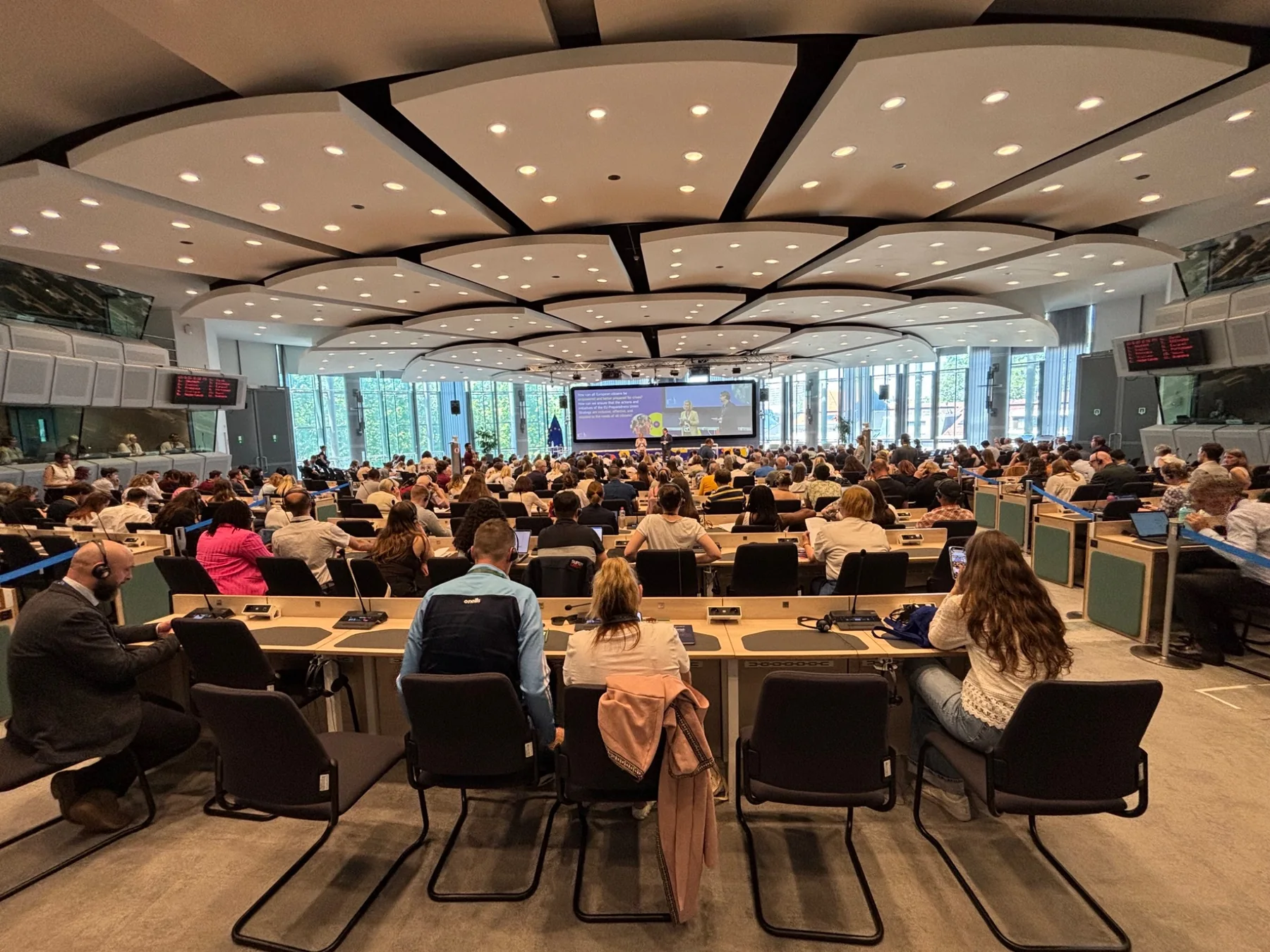 A large European meeting room filled with participants facing a stage