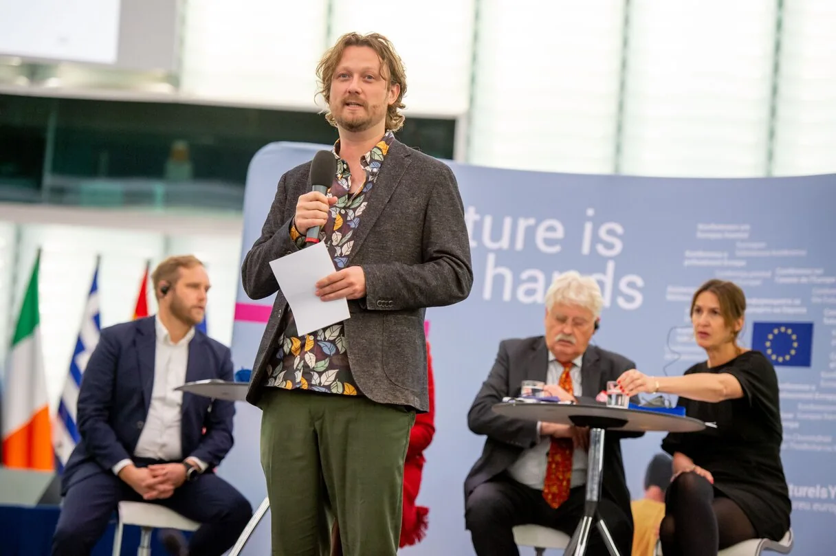 Mark speaking with a microphone during a European event