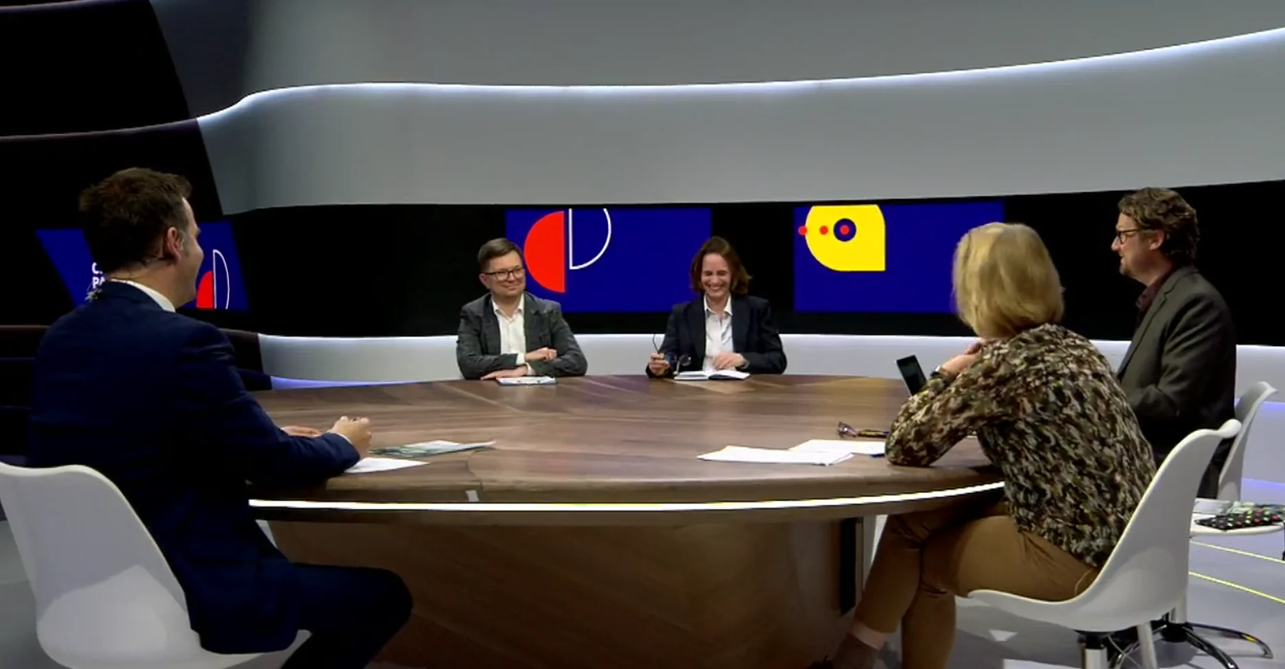 Mark participating in a moderated discussion around a studio table